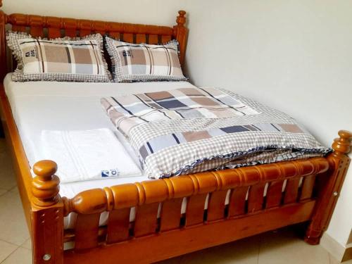 1 cama con marco de madera y almohadas en Zoe Heights Guest House, en Kampala