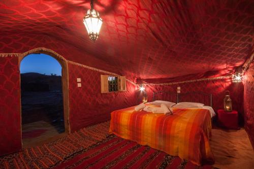 a red room with a bed in a tent at Bivouac M'hamid Le Pacha in Mhamid