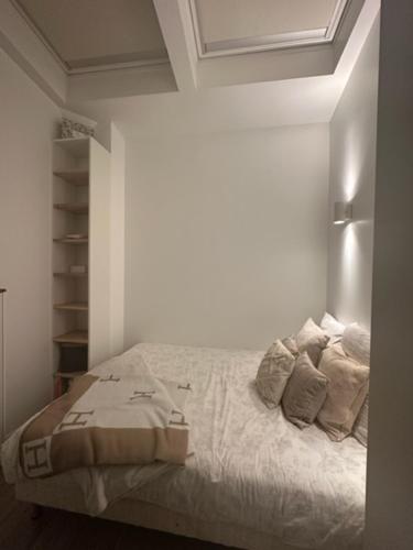 une chambre avec un lit avec des draps blancs et des oreillers dans l'établissement Studio PARIS 75010, à Paris