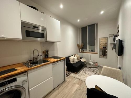 une cuisine avec des armoires blanches et un salon dans l'établissement Studio PARIS 75010, à Paris