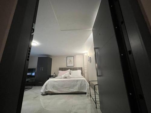 una camera da letto con un letto con lenzuola bianche e cuscini rosa di Cozy Studio in ALexandroupolis a Alexandroupoli