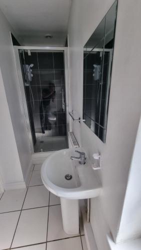 a white bathroom with a sink and a mirror at En Suite room with kitchen facilities in Nottingham