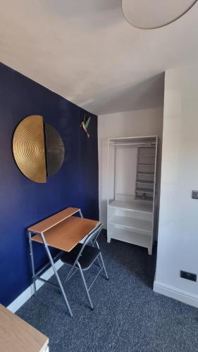 une table et une chaise dans une pièce avec un mur bleu dans l'établissement En suite room with kitchen facilities, à Nottingham