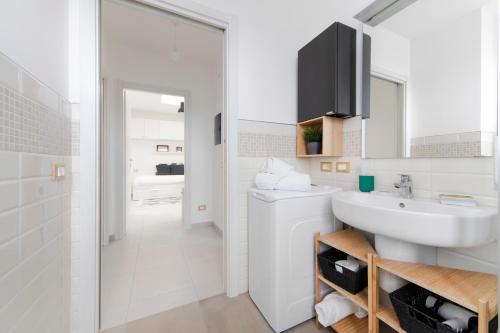 Un baño blanco con lavabo y espejo. en Realkasa Pool & Parking Flat, en Bolonia