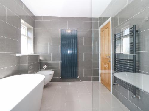 a bathroom with a tub and a toilet and a sink at Glanffraw in Aberffraw