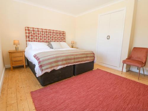 a bedroom with a bed and a red rug at Glanffraw in Aberffraw