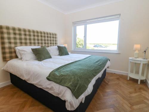 a bedroom with a large bed with a window at Glanffraw in Aberffraw