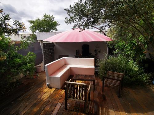 un patio con sofá y sombrilla rosa en Villa spacieuse et stylée à 50m de la plage, en Carnon-Plage