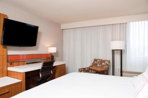 a hotel room with a bed and a flat screen tv at Sonesta Hotel Grand Rapids Airport in Grand Rapids