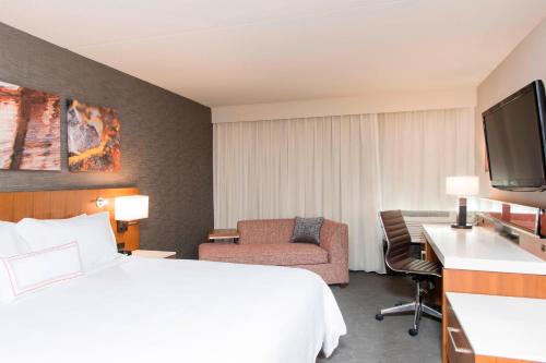 a hotel room with a bed and a chair and a television at Sonesta Hotel Grand Rapids Airport in Grand Rapids