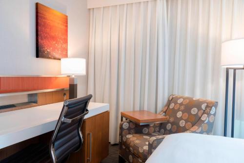 a hotel room with a bed and a chair and a desk at Sonesta Hotel Grand Rapids Airport in Grand Rapids