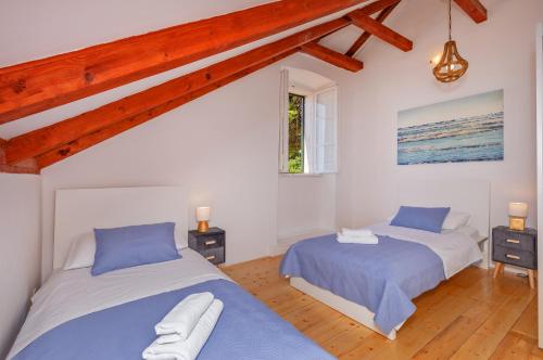 2 camas en un dormitorio con paredes blancas y vigas de madera en Tik tak Dubrovnik 2, en Dubrovnik