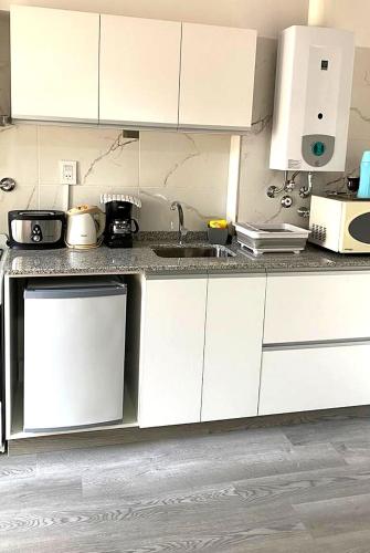 a kitchen with white cabinets and a sink at Rosales.RM - Depto completo 2 ambientes con patio. in Ramos Mejía