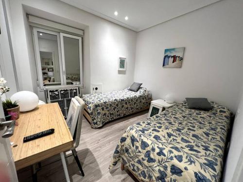 ein Zimmer mit zwei Betten und einem Tisch und einem Schreibtisch in der Unterkunft Apartamento en San Sebastián in Añorga-Lugariz