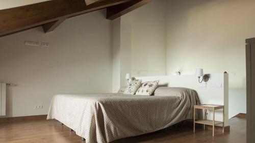 a white bedroom with a bed and a table at EL COLLADO, Ruiloba in Sierra