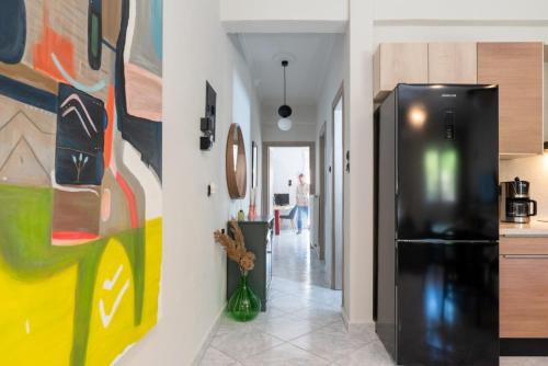 a kitchen with a black refrigerator and paintings on the wall at Old Town Apartment in Volos
