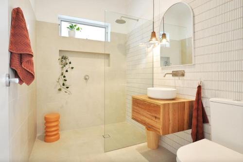 uma casa de banho com um lavatório e uma cabina de duche em vidro. em Pine at Arlos Glenelg South em Glenelg