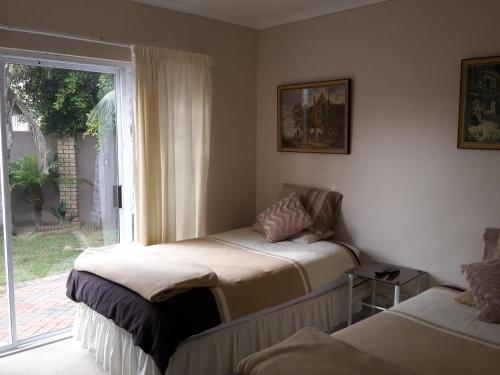 a room with two beds and a window at Abby's Guesthouse in Port Elizabeth