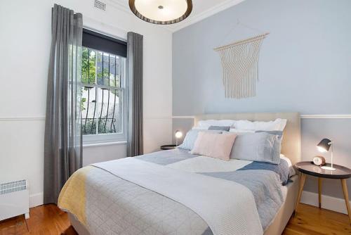 een witte slaapkamer met een bed en een raam bij Renovated cottage in CBD with Backyard in Adelaide
