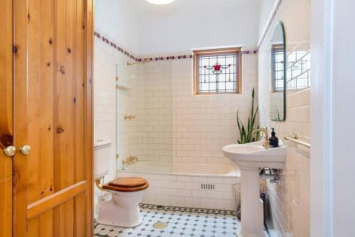 een badkamer met een toilet, een wastafel en een bad bij Renovated cottage in CBD with Backyard in Adelaide
