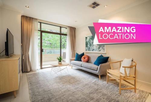 a living room with a couch and a pink amazing location sign at Serene on Grenfell Adelaide in Adelaide