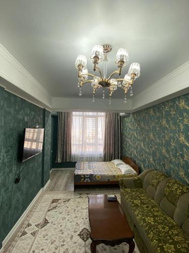 Una sala de estar con un sofá y una lámpara de araña. en 2 room apartment Цум Айчурок, en Bishkek