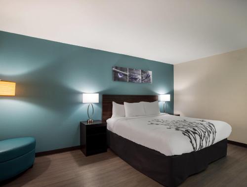 a hotel room with a bed and a blue wall at Sleep Inn Savannah Midtown in Savannah