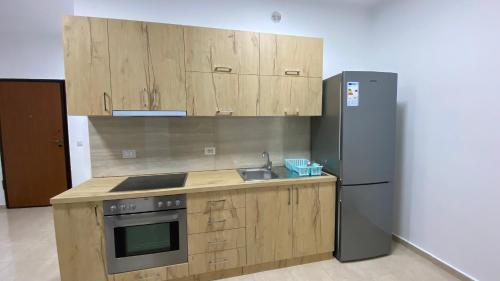 uma cozinha com armários de madeira e um frigorífico em Anna´s apartament em Lushnjë