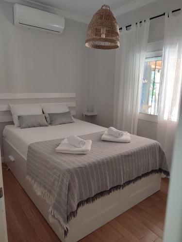 a white bedroom with a bed with two towels on it at EL RETIRO in Sanlúcar de Barrameda