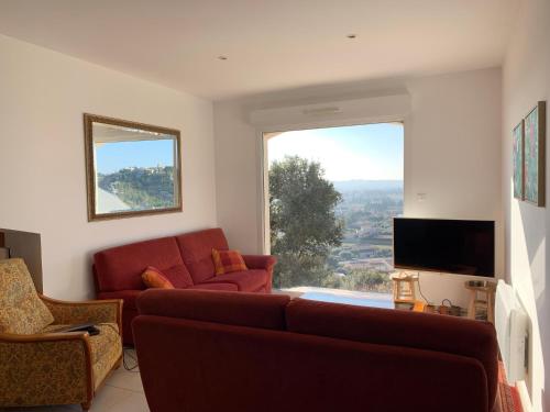 uma sala de estar com um sofá vermelho e uma grande janela em Villa Madou em Rochefort-du-Gard
