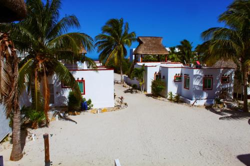 a group of houses on the beach with palm trees at Sikinos Holiday Home in Telchac Puerto