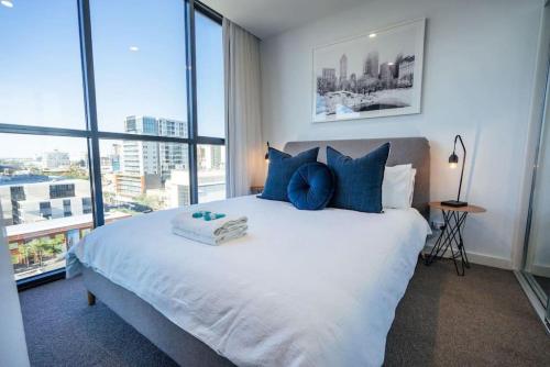 a bedroom with a large bed with blue pillows at Sky High on Grote - An Elevated Inner-City Stay in Adelaide
