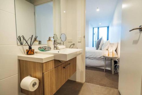a bathroom with a sink and a bedroom with a bed at Sky High on Grote - An Elevated Inner-City Stay in Adelaide