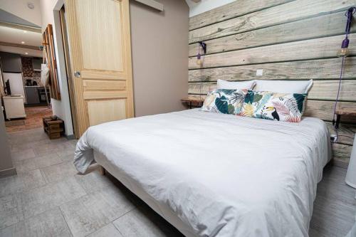 1 dormitorio con 1 cama grande y pared de madera en Domaine Demoiselles Maisonnette, en Hauteville