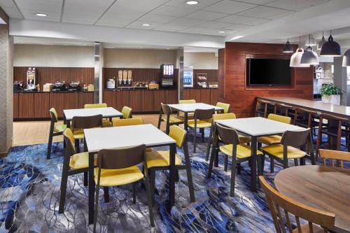ゲインズビルにあるFairfield Inn & Suites by Marriott Gainesvilleのダイニングルーム(テーブル、黄色い椅子付)