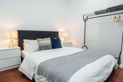 ein Schlafzimmer mit einem großen weißen Bett mit blauen Kissen in der Unterkunft Tropicana on Bent Adelaide in Adelaide