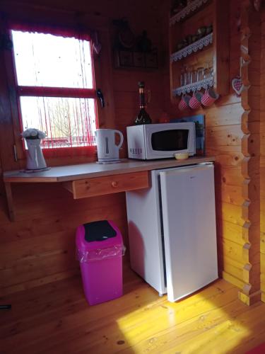 a small kitchen with a microwave and a refrigerator at Roulotte la passe pierre in Pendé