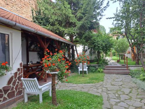 two white chairs sitting outside of a house with flowers at 7 Levél Panzió, Ultra Central, Self Check-in, Self-Catering in Miercurea-Ciuc