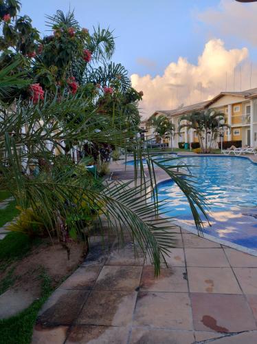 una piscina con una palmera al lado de un edificio en Recanto Taperapuan Residencial Mont Carmelo en Porto Seguro