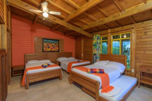 three beds in a room with wooden walls at Cabitat Cabañas in Quimbaya