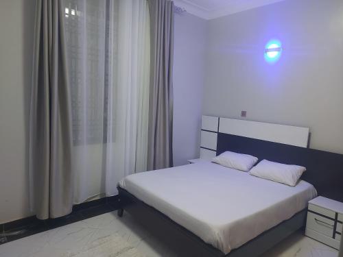 a bedroom with a bed with white sheets and a window at Precious Bahai nest 1BDR wifi Netflix in Kampala