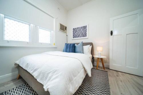 a white bedroom with a bed and a window at Seas The Day on Durham in Glenelg