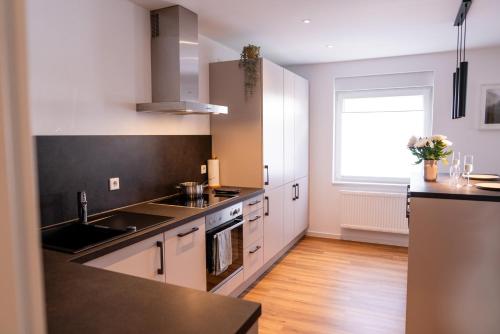 a kitchen with white cabinets and black counter tops at Exklusives Apartment in bester Lage in TBB in Tauberbischofsheim