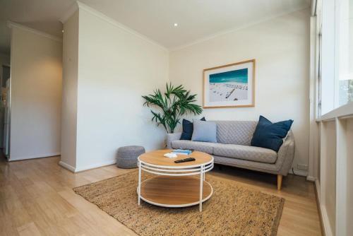 a living room with a couch and a table at Beachy Keen on Moseley in Glenelg