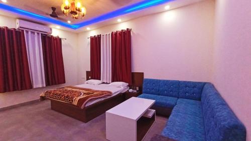 a living room with a blue couch and a bed at Lakshya Resort in Gorakhpur