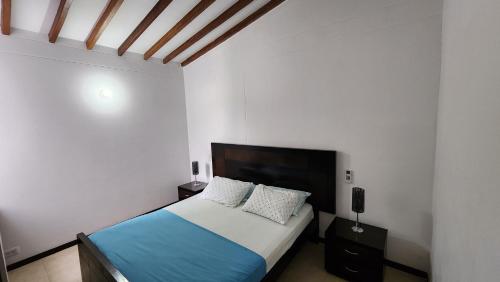 サンタ・フェ・デ・アンティオキアにあるApartasol Ciudadela Santafe - Santa Fe de Antioquiaの青いシーツと枕が備わったベッドのある寝室