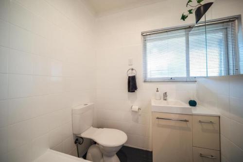 a white bathroom with a toilet and a sink at Urban Beach Shack Grange in Grange