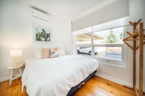 a bedroom with a large white bed and a window at Urban Beach Shack Grange in Grange