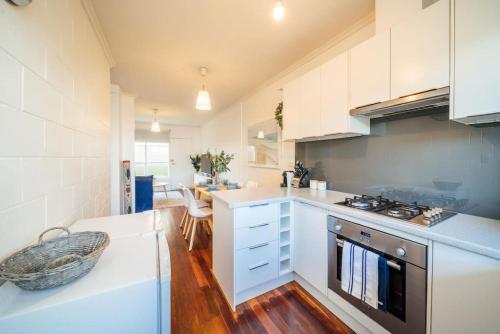 a kitchen with white cabinets and a stove top oven at Urban Beach Shack Grange in Grange