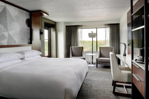 une chambre d'hôtel avec un lit, une table et des chaises dans l'établissement Marriott East Lansing at University Place, à Lansing
